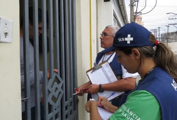 Imagem de agentes da vigilância sanitária conversando com morador - Metrópoles