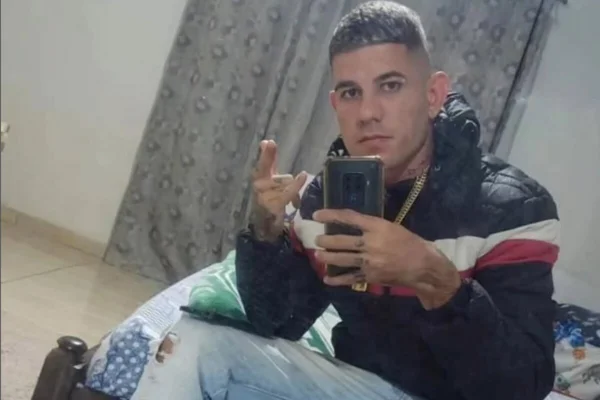Homem branco, sem barba cabelo curto, usando camiseta de moletm com capuz, preto, calça jeans, sentado em cama - Metrópoles