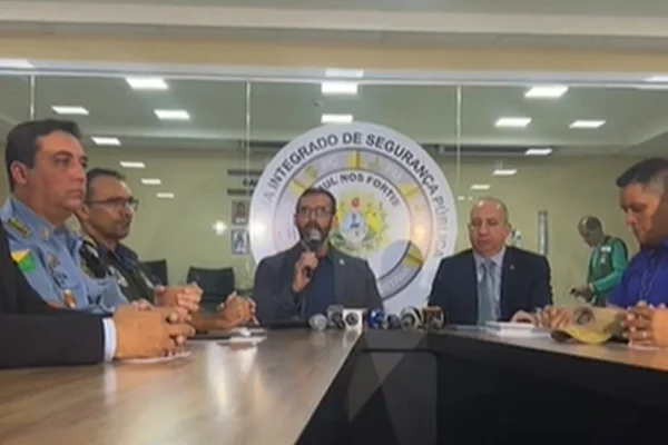 imagem colorida mostra cinco homens sentados em mesa durante coletiva de imprensa sobre rebelião em presídio de segurança máxima no acre