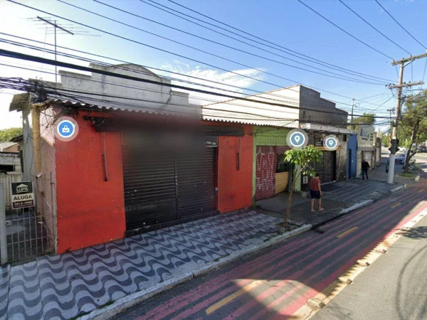 Foto colorida mostra estabelecimento com fachada vermelha e portão preto. O dia é ensolarado - Metrópoles