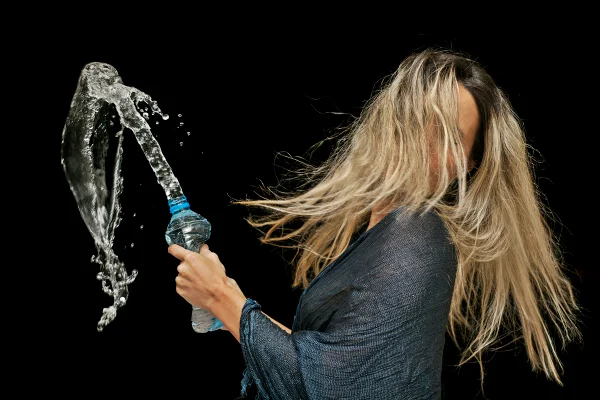 Foto colorida de mulher com garrafa esguichando