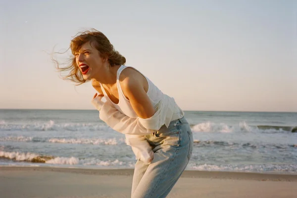 Taylor Swift ri na praia em foto de divulgação do álbum 1989 - Metrópoles