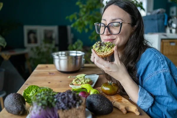 Foto colorida de mulher comendo pão - Metrópoles