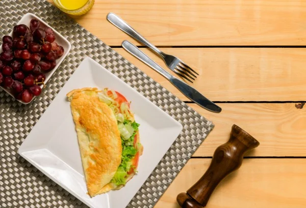 Crepioca de abobrinha em um prato branco com salada e uvas - Metrópoles