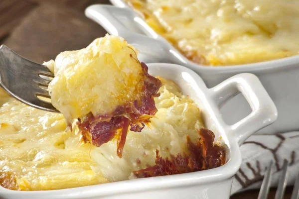escondidinho de carne seca servido em refratário branco e garfo com pedaço