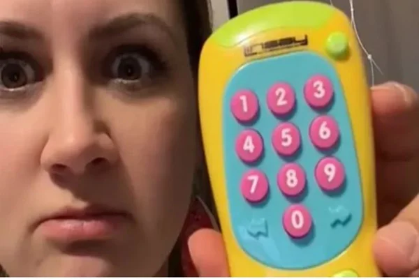 Imagem colorida de uma mulher branca segurando um brinquedo que contém botões rosas