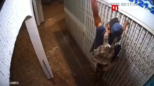 Homem se apoiando em comparsa para roubar lâmpada
