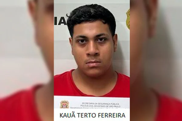 Imagem colorida de homem de camisa vermelha preso. Metrópoles
