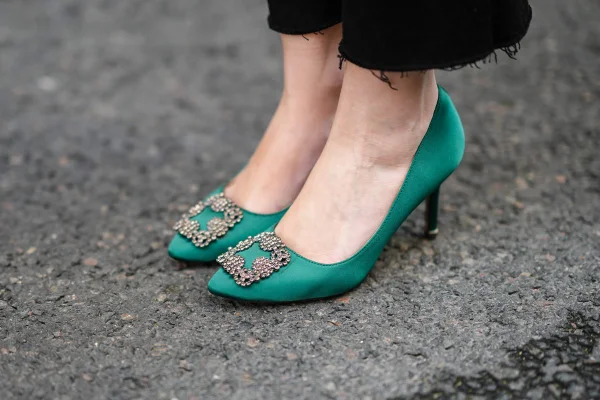 Sandália de salto fino azul turquesa, com uma fivela brilhosa na frente, da marca Manolo Blahnik.