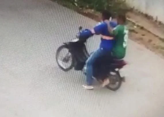 Imagem colorida de câmera de segurança captura o momento em que a dupla de criminosos assalta um homem e leva sua moto após balear policial penal dentro de casa