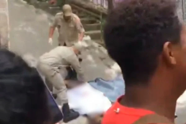 Foto colorida de policias cobrindo corpo em favela no Rio - Metrópoles