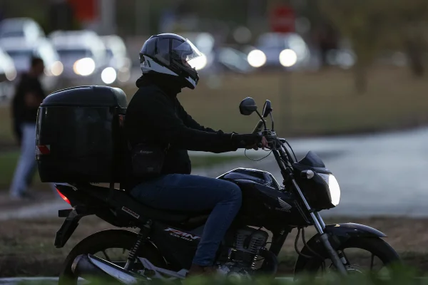 Imagem colorida de um homem em uma moto, usando capacete com a viseira levantada - Metrópoles