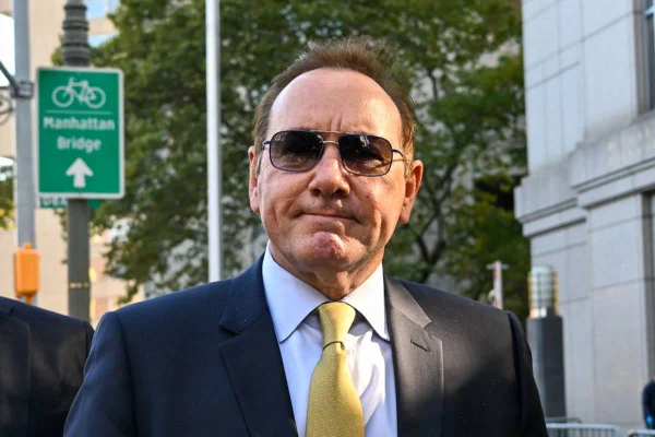 kevin spacey de camisa azul clara, blazer preto e gravata dourada posa serio com oculos de sol - metrópoles