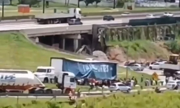 Imagem colorida mostra caminhão sendo saqueado por pessoas após sofrer acidente perto da rodovia Dutra, no interior de São Paulo