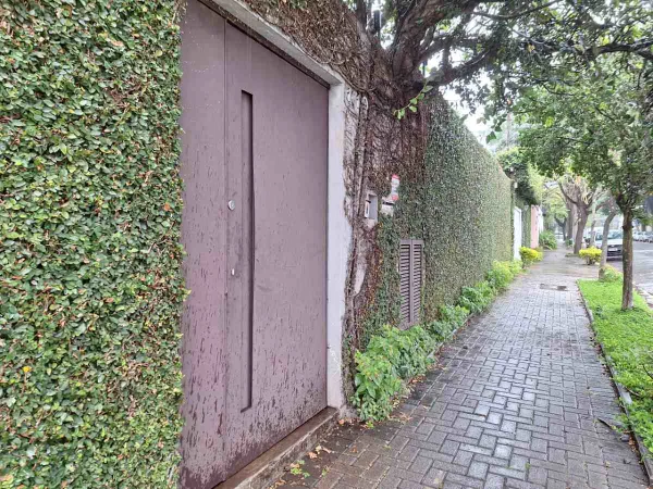 foto colorida de fachada de casa com portão escuro e muro alto em SP - Metrópoles