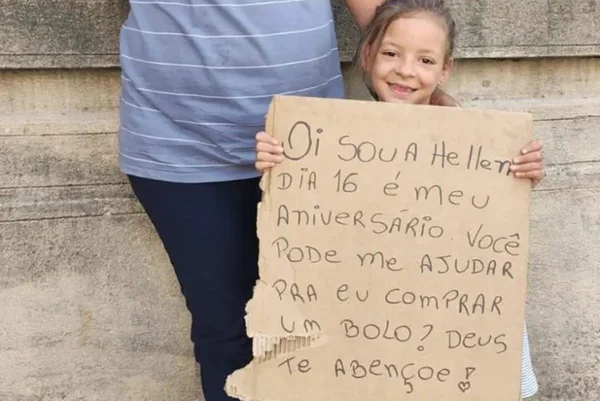 Imagem colorida de criança segurando cartaz e pedindo ajuda para comprar um bolo de aniversário - Metrópoles
