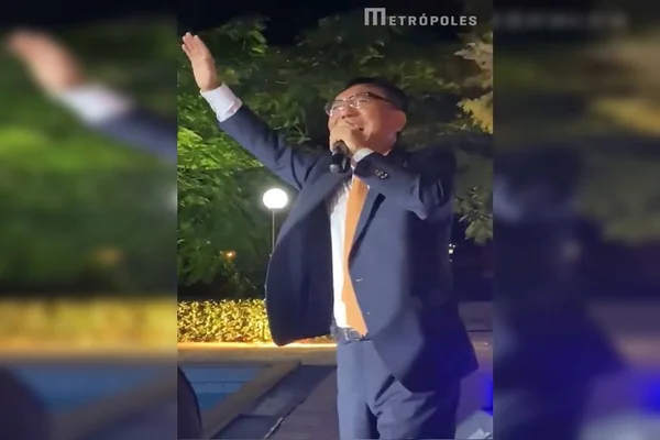 Homem de terno azul com a mão pra cima