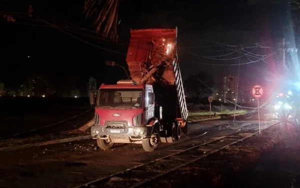 Caminhão com caçamba elevada acerta fios e poste