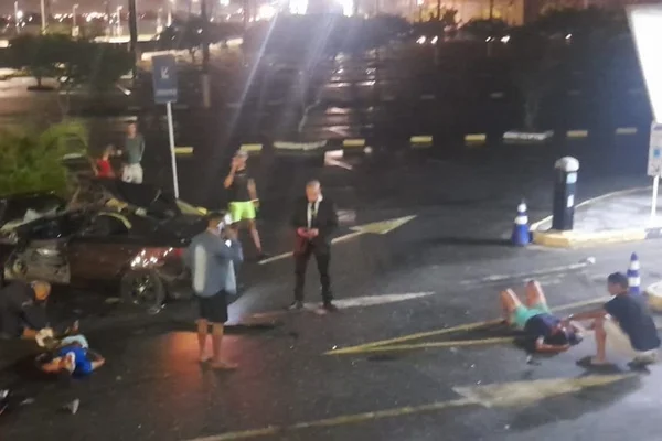 Foto colorida de carro e pessoas feridas em estacionamento de shopping - Metrópoles