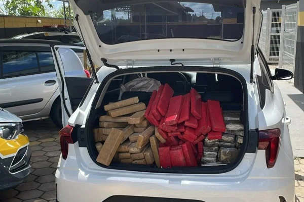 imagem colorida de carro branco com porta-malas aberto contendo mais de 200 tijolos de maconha apreendidos com dois adolescentes - Metrópoles