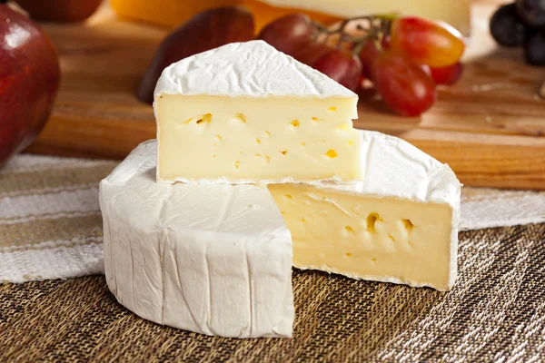 Queijo Brie branco orgânico fresco em um fundo. Metrópoles