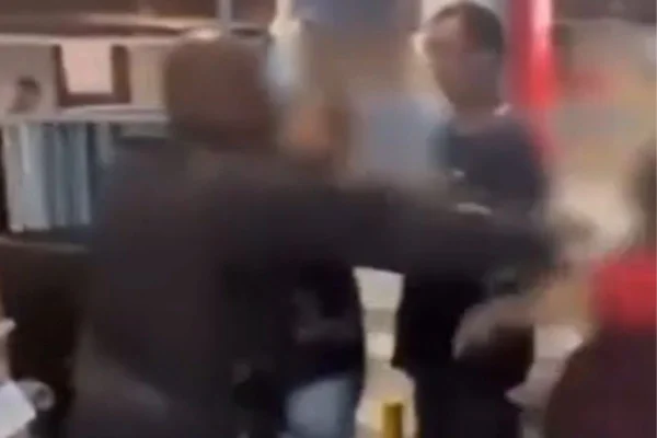 Foto colorida e borrada de PM a agredindo mulher de 65 anos com coronhada de fuzil em bar no Rio - Metrópoles