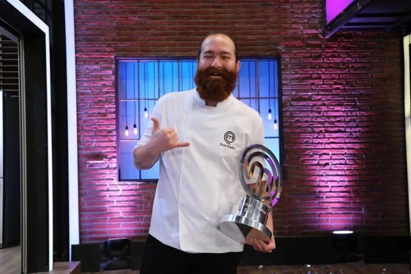 Foto de Eren Kasikci, vencedor do MasterChef Turquia em 2021. Ele está de avental, sorrindo, e segura o troféu da competição - Metrópoles