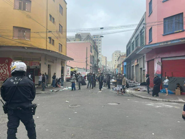 Foto colorida mostra usuários de drogas da Cracolândia concentrados sob escolta da GCM