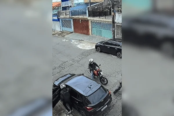 Imagem colorida de dupla de assaltantes cometendo roubo contra motorista de carro - Metrópoles