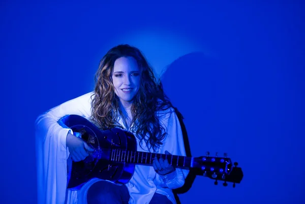 Fotografia colorida mostrando mulher sentada tocando violão-Metrópoles