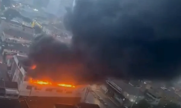 Imagem colorida de estabelecimento pegando fogo, exalando fumaça preta no céu - Metrópoles