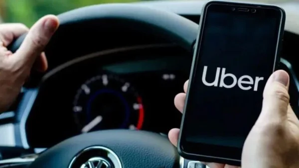 Imagem colorida de mão segurando um celular no aplicativo da Uber - Metrópoles