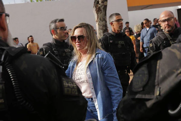 Fotografia colorida de mulher de óculos de sol andando em meio a policiais