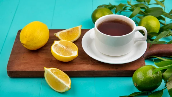 Xícara de café em cima de tábua de madeira ao lado de limões