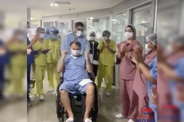 Idoso sendo aplaudido por corpo médico do Hospital Home