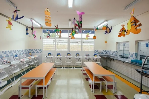 Imagem colorida mostra refeitório de uma creche - Metrópoles