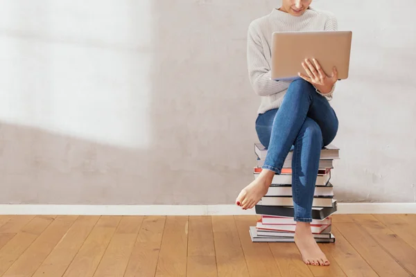 Mulher sentada em livros com notebook