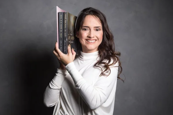 Imagem colorida mostra escritora segurando livros - Metrópoles
