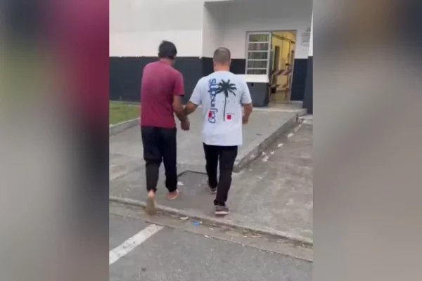 Imagem colorida mostra homem sendo conduzido a delegacia após ser preso por estuprar o enteado de 5 anos - Metrópoles