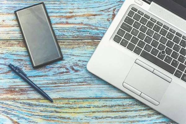 Na foto, há um celular, uma caneta e um notebook em cima de uma mesa - Metrópoles