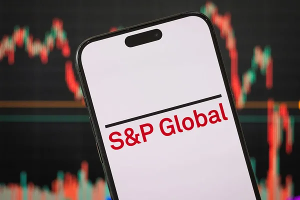 Imagem de um aparelho celular sendo segurado. Na tela, o logotipo da S&P Global, em letras vermelhas - Metrópoles