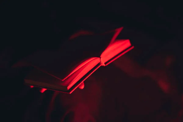 Livro com luz vermelha mostra pessoa folheando as páginas - Metrópoles