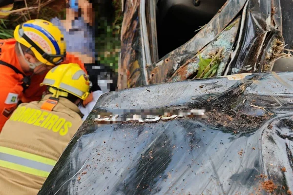 Bombeiros resgatando motorista de carro capotado