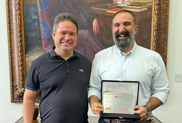 Foto colorida do secretário da Casa Civil de SP, Arthur Lima, à esquerda de camisa escura, ao lado de João Germano Böttcher Filho, que era seu chefe de gabinete, de barba, camisa clara e segurando uma placa - Metrópoles