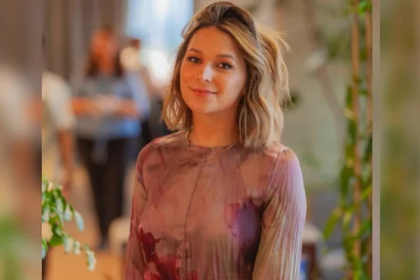 Foto de Mariana Cavanha com fundo desfocado, ela é loira usa uma blusa rosa - Metrópoles