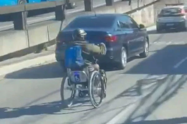 Imagem colorida, homem usando cadeira de rodas para trafegar no trãnsito- Metrópoles