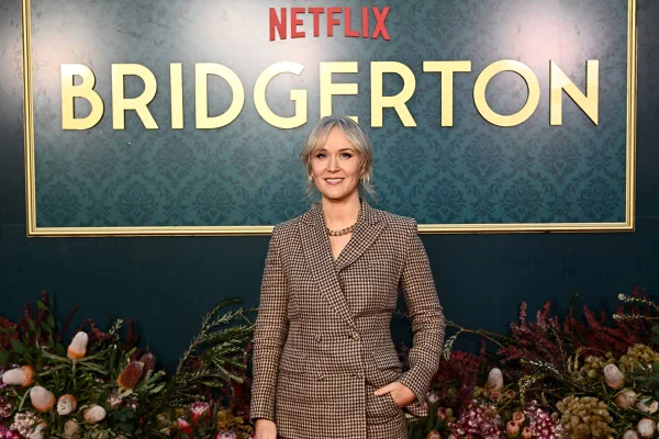 Na imagem colorida, mulher posa para foto em tapete vermelho. Ela usa terno quadriculado - Metrópoles