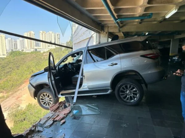 Imagem colorida de carro de luxo suspenso com as rodas dianteiras do lado de fora de um prédio em BH - Metrópoles