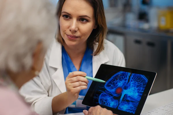 Foto colorida de médica segurando tablet e mostrando cérebro de paciente - Metrópoles