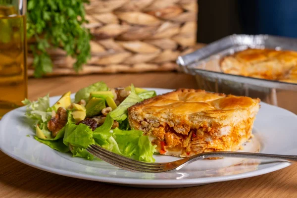 Prato de cerâmica com fatia de torta de frango e salada